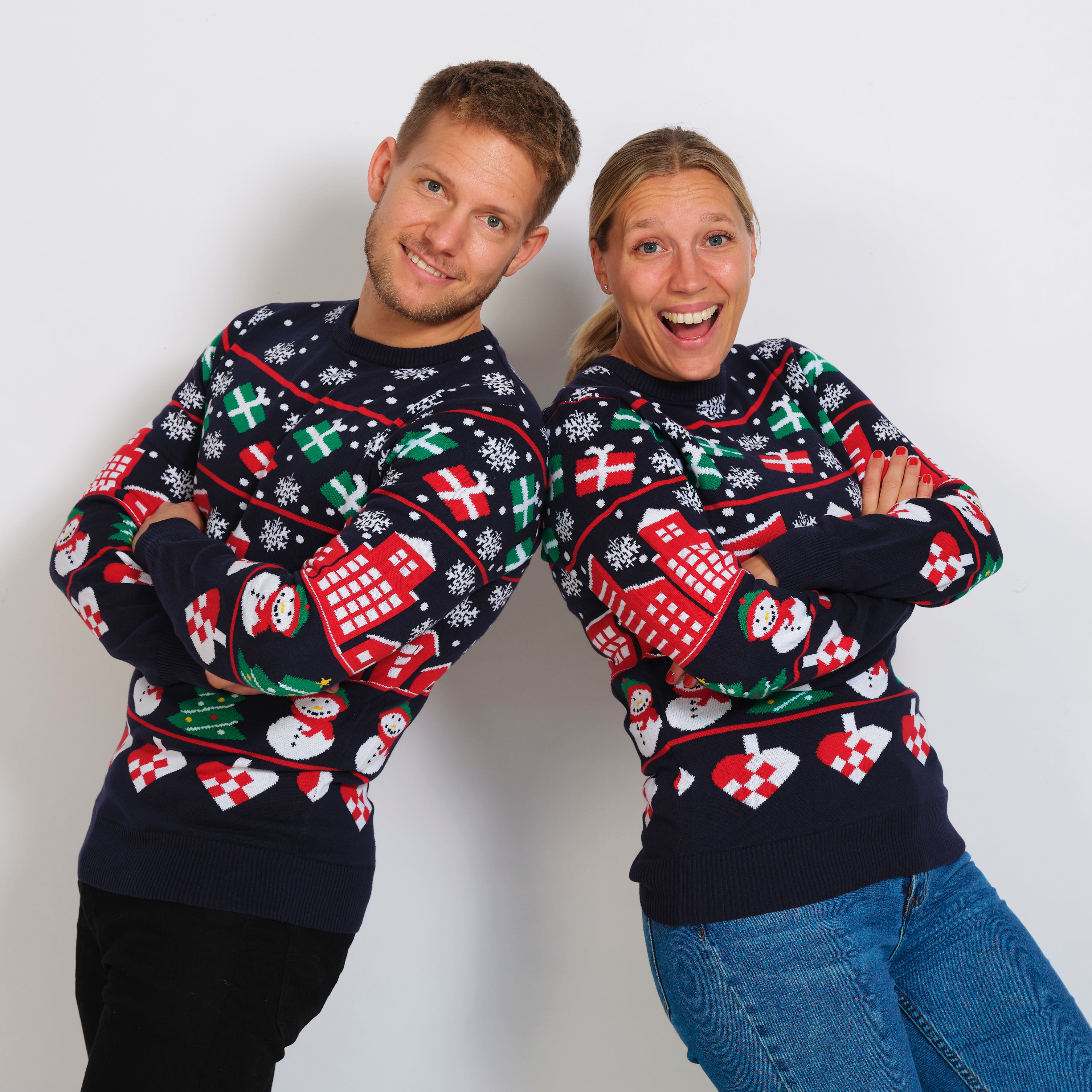 En smilende mann og kvinne iført julegenser med snøfnugg og gaver.